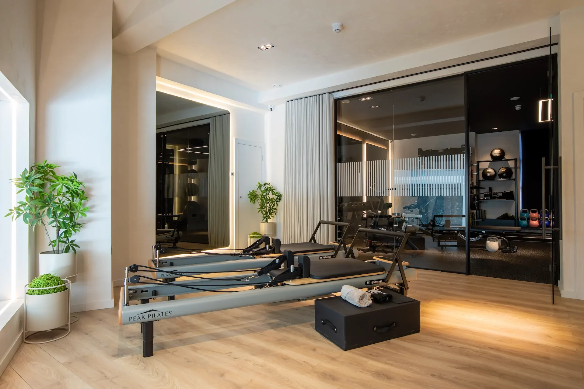 Modern Pilates studio with reformer machines, mirrors, and natural lighting.